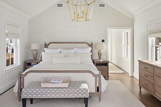 bedroom featuring hardwood / wood-style flooring, crown molding, lofted ceiling, and a notable chandelier