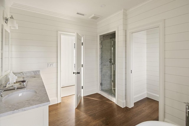 bathroom featuring wood-type flooring, wooden walls, a shower with door, vanity, and ornamental molding