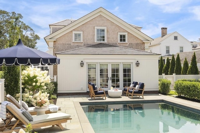 rear view of property featuring a fenced in pool, a patio area, outdoor lounge area, and french doors