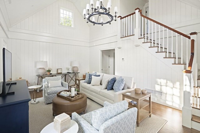 living room with high vaulted ceiling, wood-type flooring, and an inviting chandelier