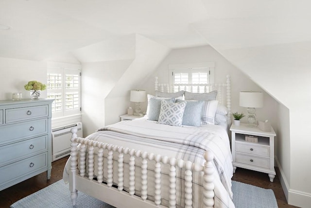 bedroom featuring vaulted ceiling, multiple windows, and dark wood-type flooring