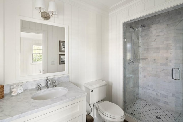 bathroom featuring toilet, vanity, a shower with shower door, and ornamental molding