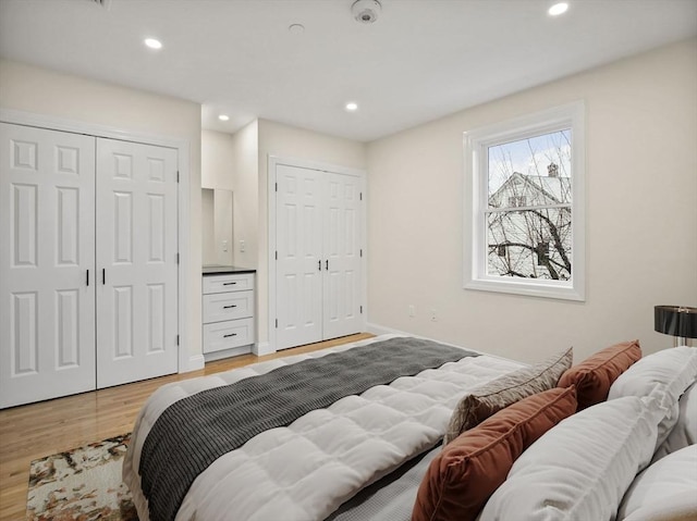 bedroom featuring multiple closets and light hardwood / wood-style flooring