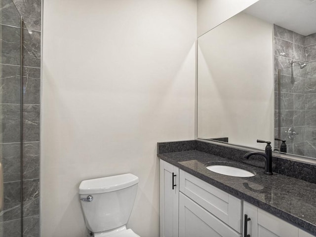 bathroom with tiled shower, vanity, and toilet