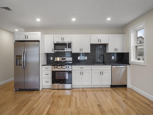 kitchen with stainless steel appliances, white cabinets, and sink