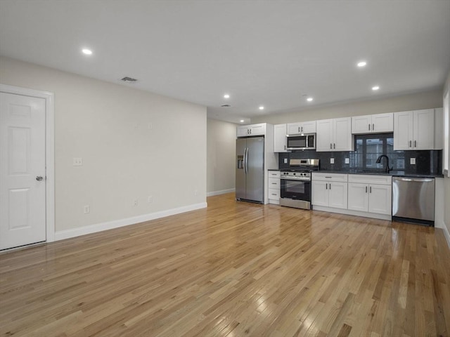 kitchen featuring light wood-type flooring, appliances with stainless steel finishes, white cabinetry, and sink