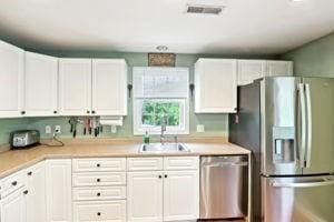 84 E Ave, Lowell, MA 01854 - kitchen with stainless steel appliances, a sink, light countertops, and white cabinets