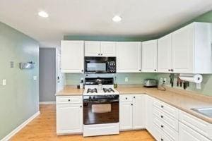 84 E Ave, Lowell, MA 01854 - kitchen with black microwave, white gas range oven, light countertops, white cabinets, and recessed lighting
