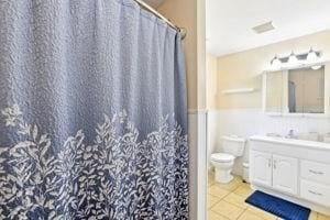84 E Ave, Lowell, MA 01854 - full bathroom featuring vanity, toilet, tile patterned floors, a wainscoted wall, and curtained shower