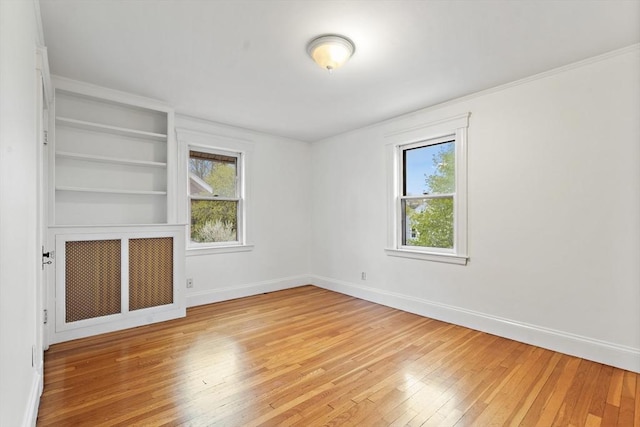 interior space with baseboards, light wood finished floors, built in shelves, and radiator