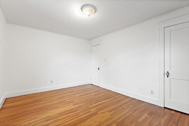 empty room with crown molding, baseboards, and light wood finished floors
