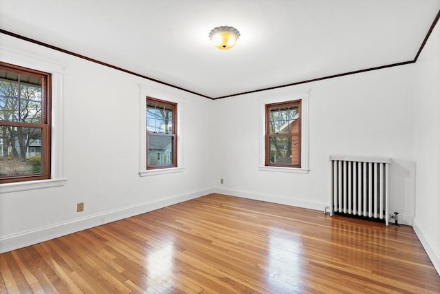 unfurnished room with plenty of natural light, light wood finished floors, and radiator heating unit