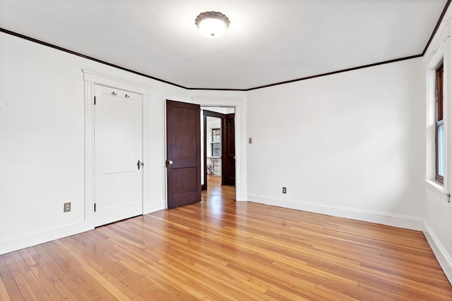unfurnished bedroom featuring baseboards, light wood finished floors, and crown molding