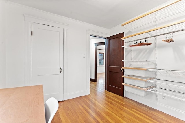 interior space with crown molding, baseboards, and light wood-type flooring