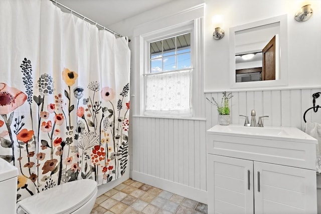 full bathroom with toilet, a shower with curtain, wainscoting, and vanity