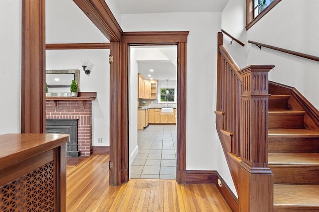 stairs featuring a brick fireplace, baseboards, and hardwood / wood-style floors