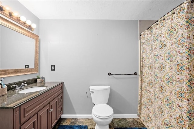 bathroom with toilet, a shower with curtain, vanity, and baseboards