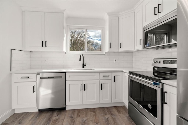 kitchen with appliances with stainless steel finishes, dark wood-style flooring, light countertops, and a sink