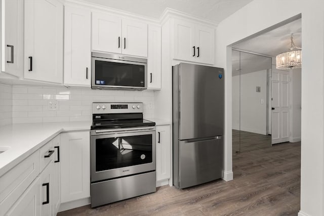 kitchen with tasteful backsplash, appliances with stainless steel finishes, dark wood-type flooring, light countertops, and white cabinetry