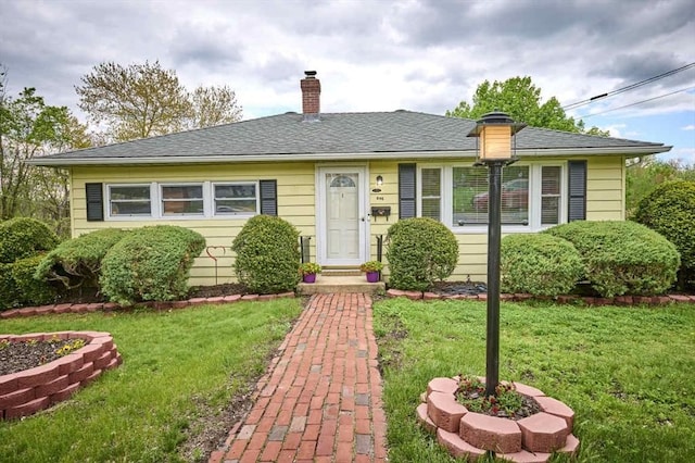 bungalow-style house with a chimney and a front lawn