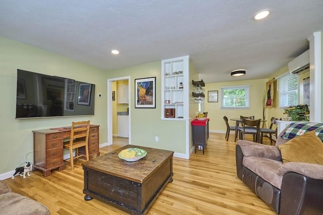 living room with light wood finished floors, baseboards, a wall unit AC, and recessed lighting
