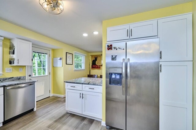 kitchen with stainless steel appliances, stone counters, light wood-style floors, white cabinetry, and recessed lighting