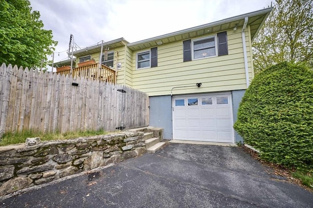 view of home's exterior featuring a garage, driveway, and fence