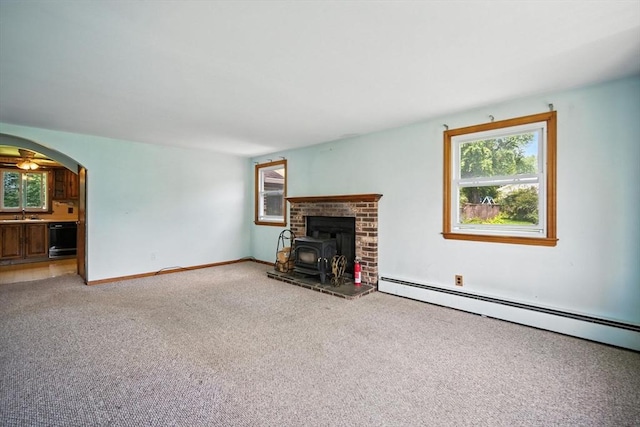 69 Michael St, Ludlow, MA 01056 - unfurnished living room with a wood stove, light colored carpet, baseboard heating, and arched walkways