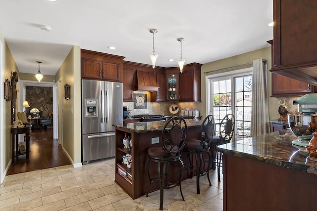 kitchen featuring stainless steel refrigerator with ice dispenser, pendant lighting, custom exhaust hood, and tasteful backsplash