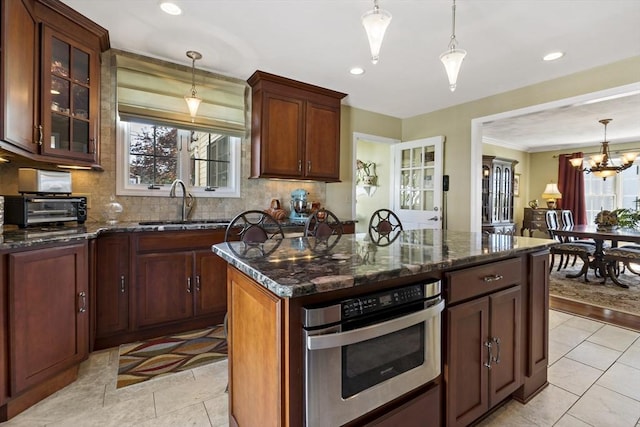 kitchen featuring tasteful backsplash, a sink, a toaster, dark stone countertops, and stainless steel oven