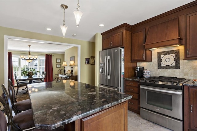 kitchen featuring backsplash, a notable chandelier, appliances with stainless steel finishes, and dark stone countertops