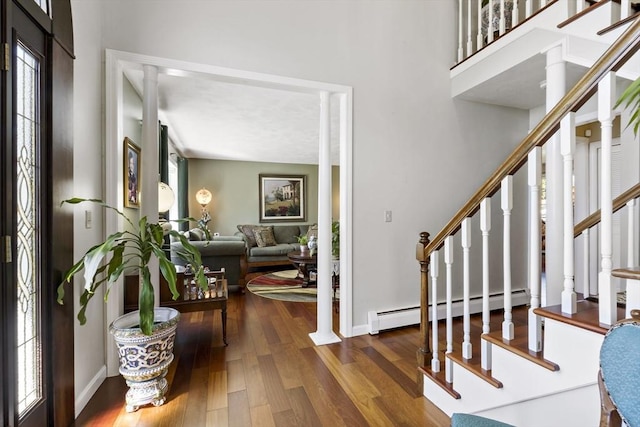 foyer entrance featuring stairway, baseboards, baseboard heating, and wood finished floors