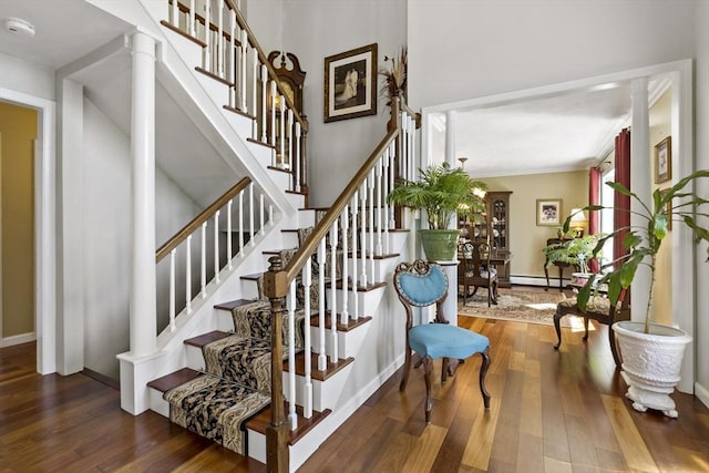 staircase with baseboards, a baseboard heating unit, and wood finished floors
