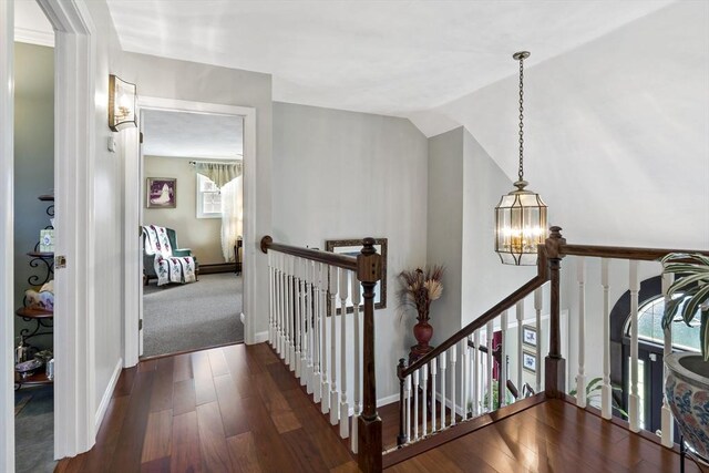 stairway with baseboards, a notable chandelier, wood finished floors, and lofted ceiling