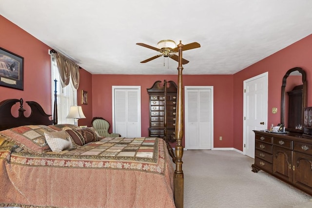 bedroom with two closets, a ceiling fan, baseboards, and light colored carpet