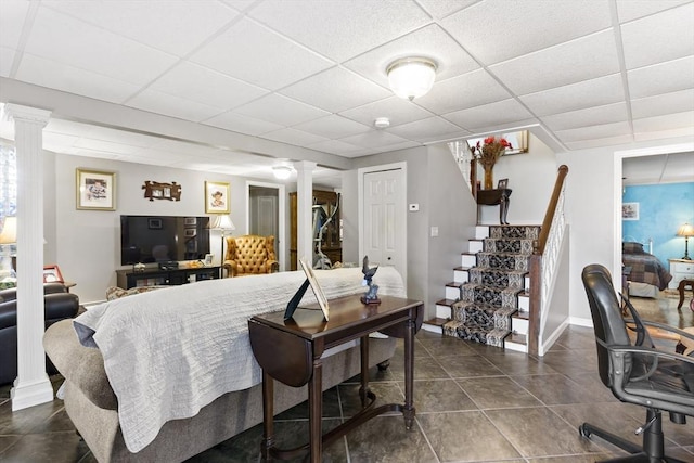 bedroom featuring ornate columns, a paneled ceiling, baseboards, and dark tile patterned flooring