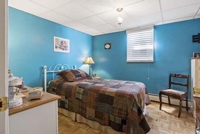 bedroom featuring baseboards, a baseboard heating unit, and a paneled ceiling