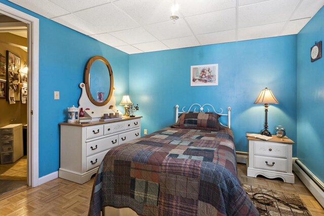 bedroom with baseboards, a baseboard heating unit, a drop ceiling, and a baseboard radiator