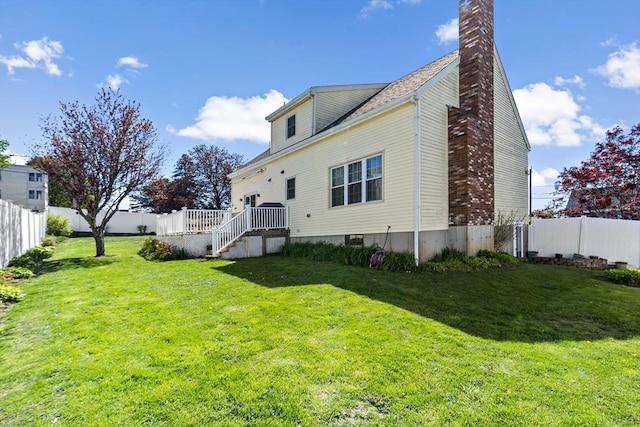 back of property with a lawn, a chimney, and a fenced backyard
