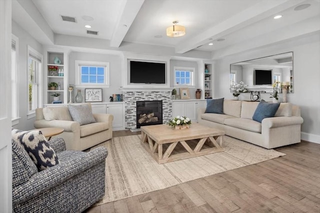 33 Central Ave Unit 12, Scituate, MA 02050 - living room with light wood finished floors, beam ceiling, a tiled fireplace, built in features, and recessed lighting