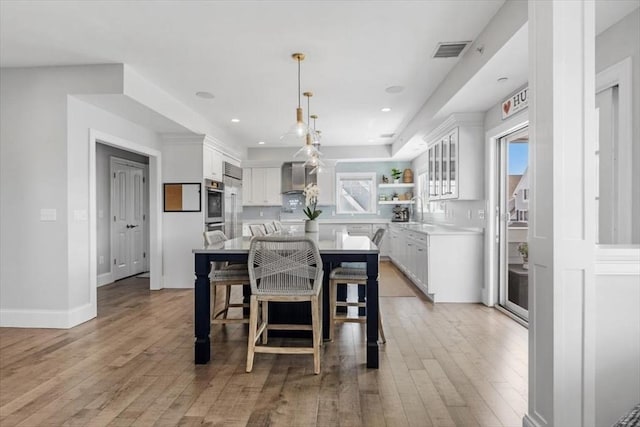 33 Central Ave Unit 12, Scituate, MA 02050 - kitchen featuring wall chimney range hood, light countertops, white cabinets, a kitchen island, and recessed lighting