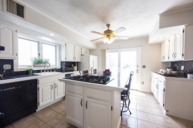 3 Nira St, Malden, MA 02148 - kitchen with black appliances, decorative backsplash, ceiling fan, white cabinets, and healthy amount of natural light