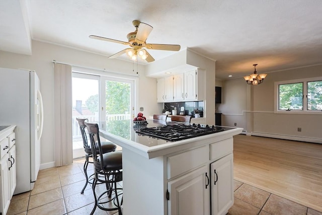 3 Nira St, Malden, MA 02148 - kitchen featuring black gas stovetop, freestanding refrigerator, a baseboard radiator, a chandelier, and white cabinetry