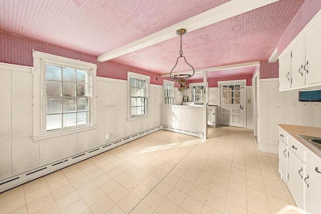 kitchen featuring decorative light fixtures, white cabinets, beam ceiling, baseboard heating, and a textured ceiling