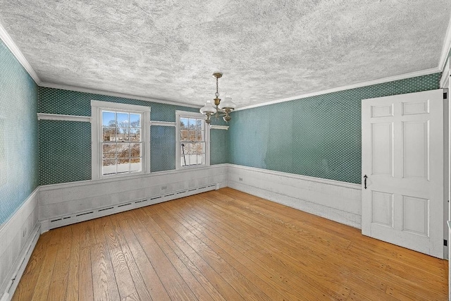 unfurnished dining area with crown molding, wood-type flooring, a chandelier, a textured ceiling, and a baseboard heating unit