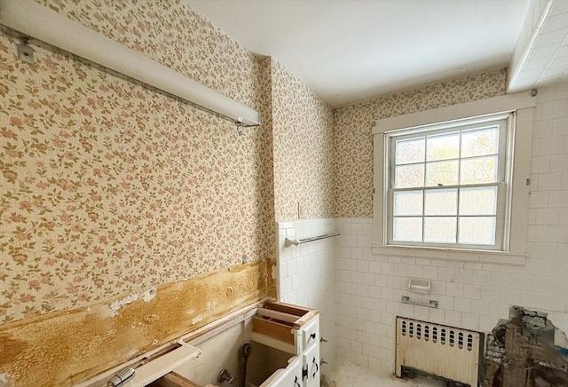 bathroom featuring radiator and tile walls