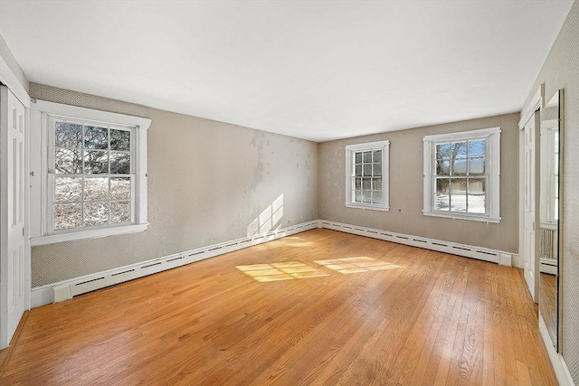 unfurnished room with a baseboard radiator and light hardwood / wood-style flooring