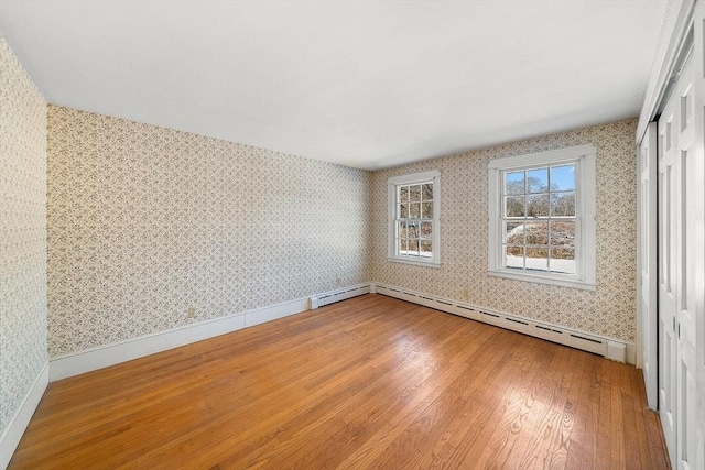 empty room with wood-type flooring and a baseboard radiator