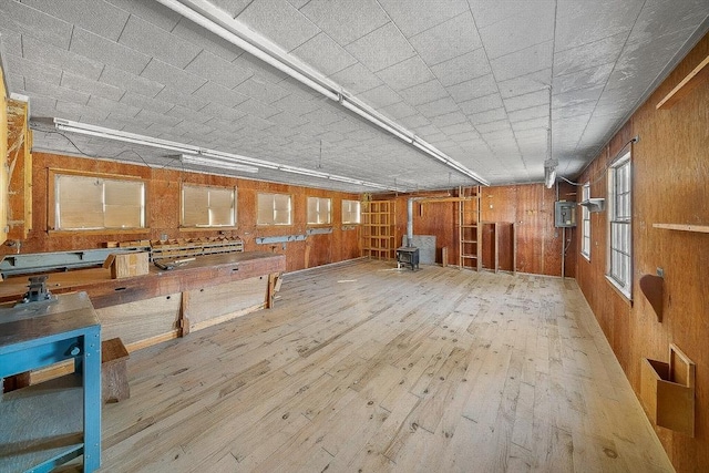 miscellaneous room with hardwood / wood-style floors, wood walls, and a wood stove