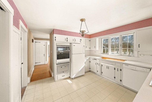 kitchen with pendant lighting, white cabinets, and white appliances